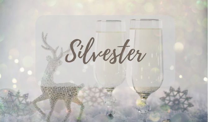 Zwei Gläser Champagner stehen auf einem Tisch, im Hintergrund ist ein Hirsch zu sehen.