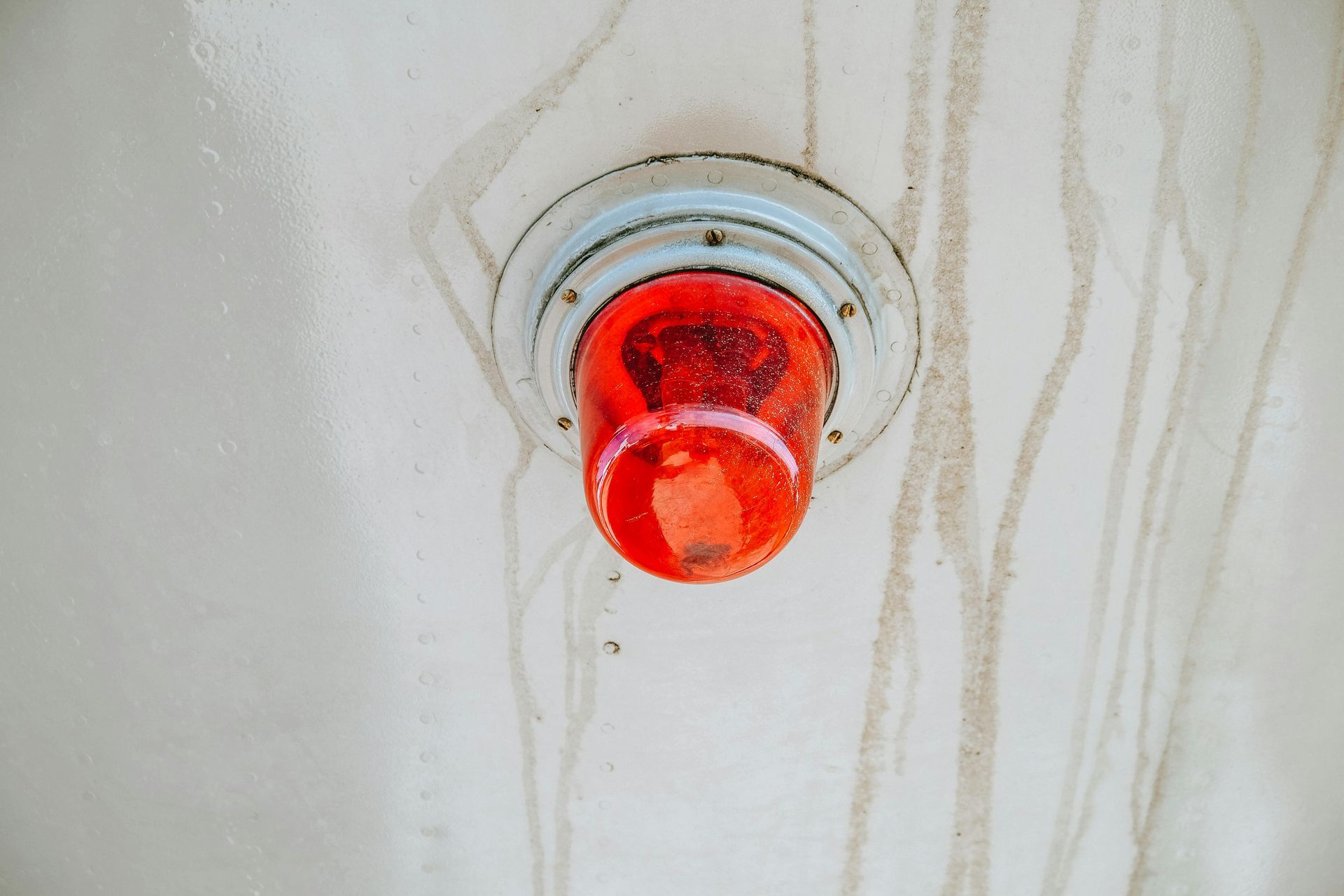 Woman in straw hat smiles, holding wine glass near a lake.