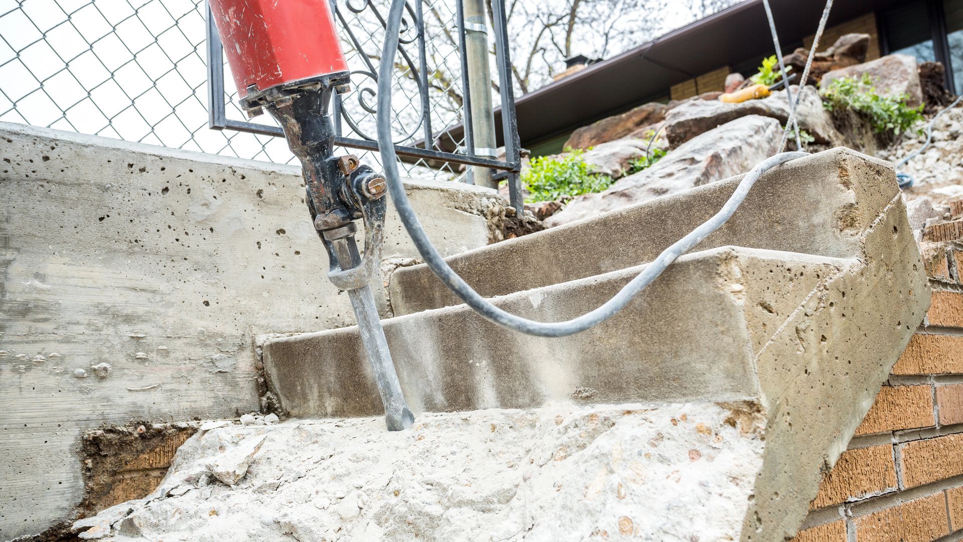 removing concrete steps from on top of a brick wall with a large hydraulic breaker