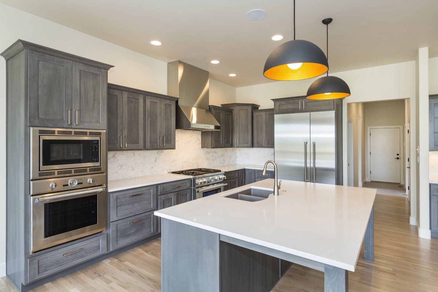 A kitchen with gray cabinets , stainless steel appliances , and a large island.