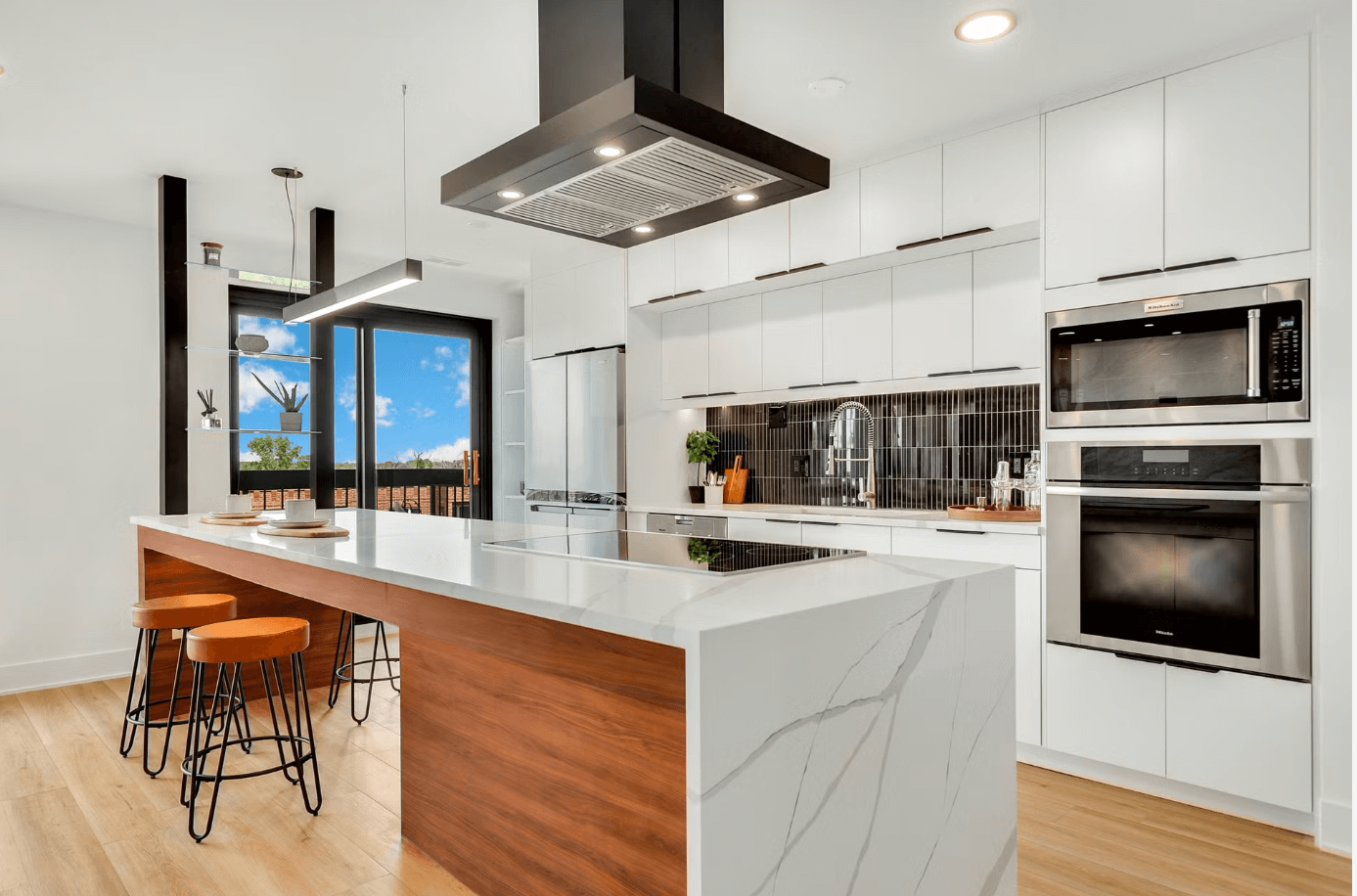 A kitchen with white cabinets and stainless steel appliances and a large island.