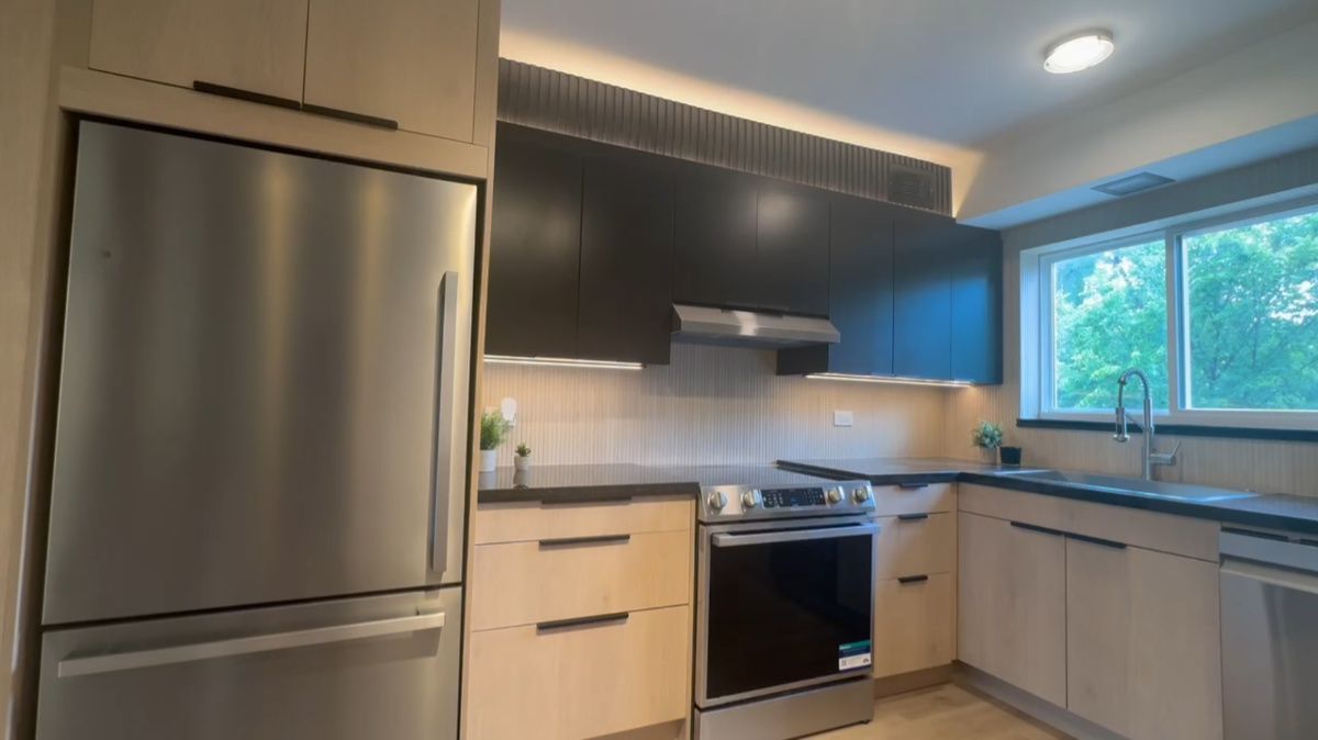 A kitchen with stainless steel appliances , wooden cabinets , a refrigerator , stove and sink.