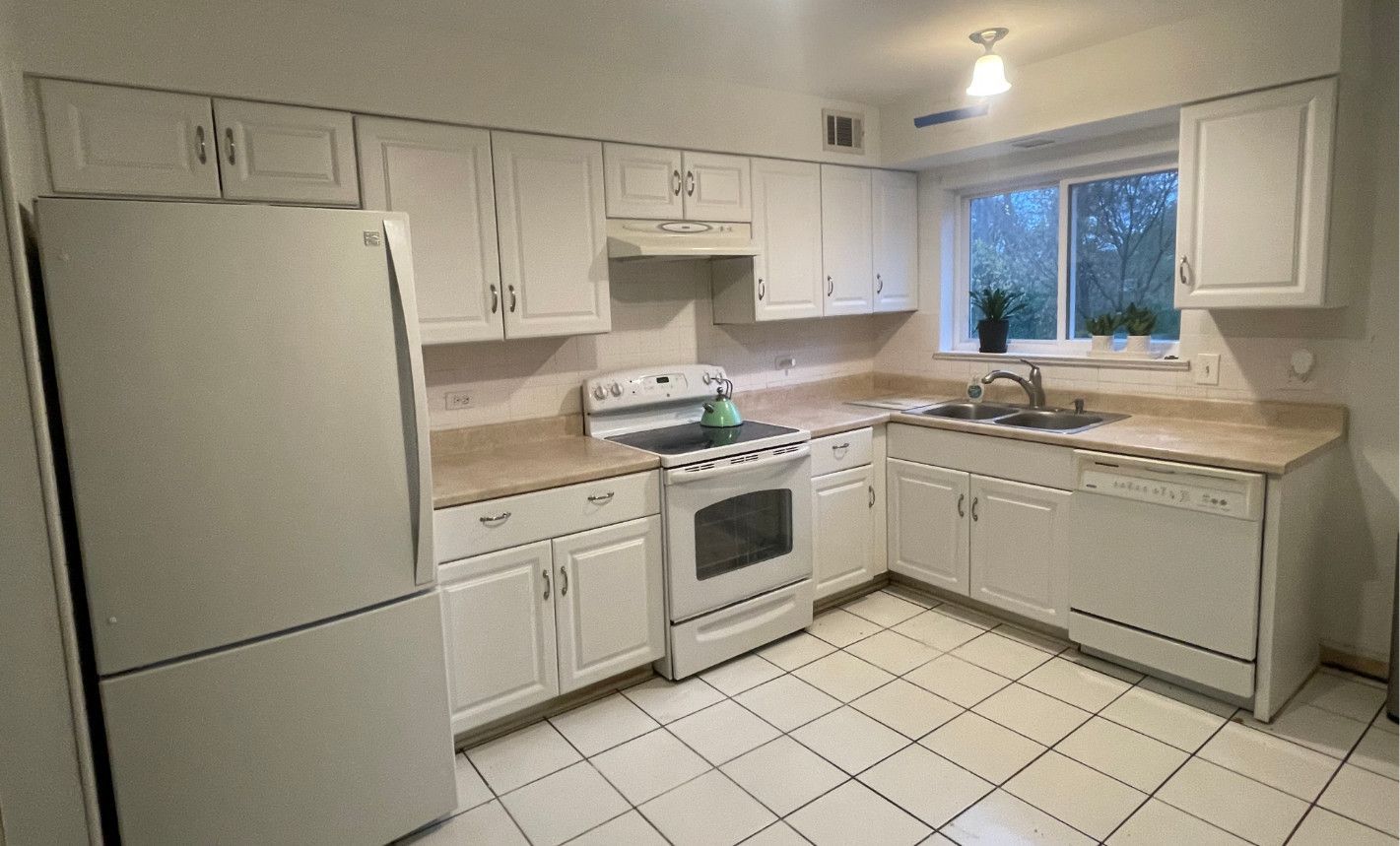 A kitchen with white cabinets , a refrigerator , a stove , and a sink.