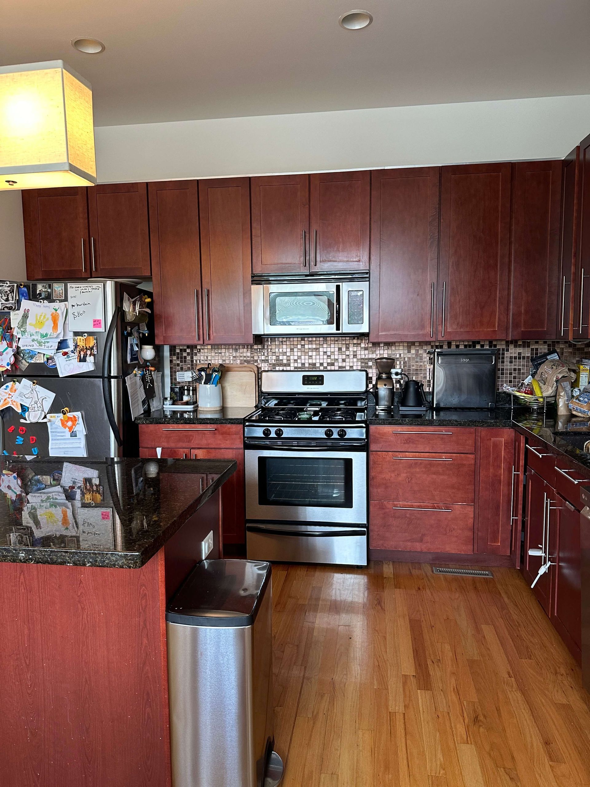 A kitchen with stainless steel appliances , granite counter tops , and wooden cabinets.