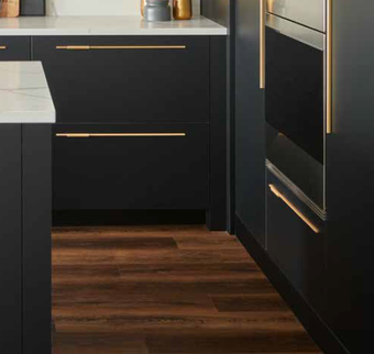 A kitchen with black cabinets and wooden floors.