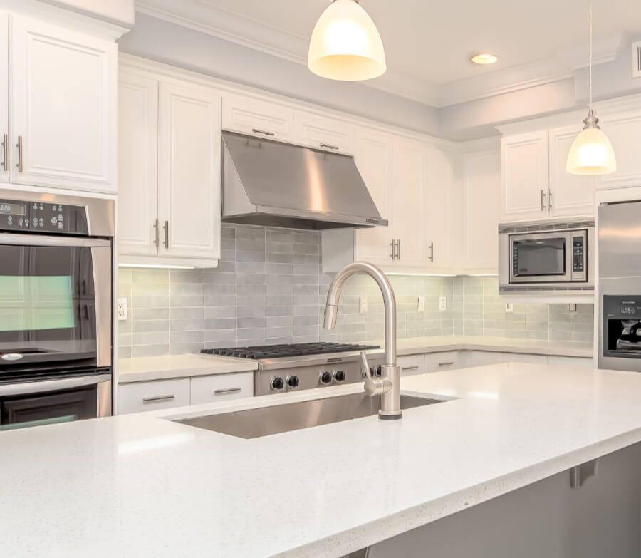 A kitchen with white cabinets , stainless steel appliances , a sink , and a stove.