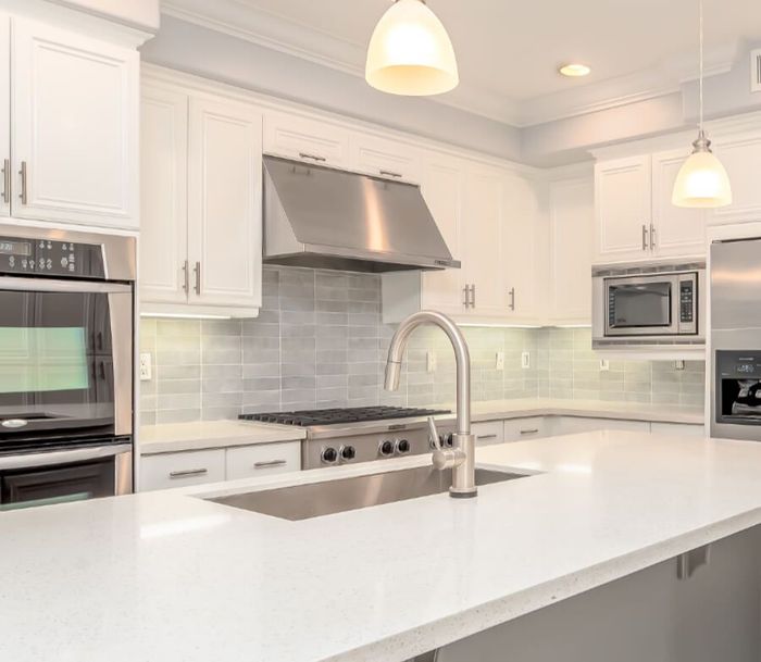 A kitchen with white cabinets , stainless steel appliances , a sink , and a stove.