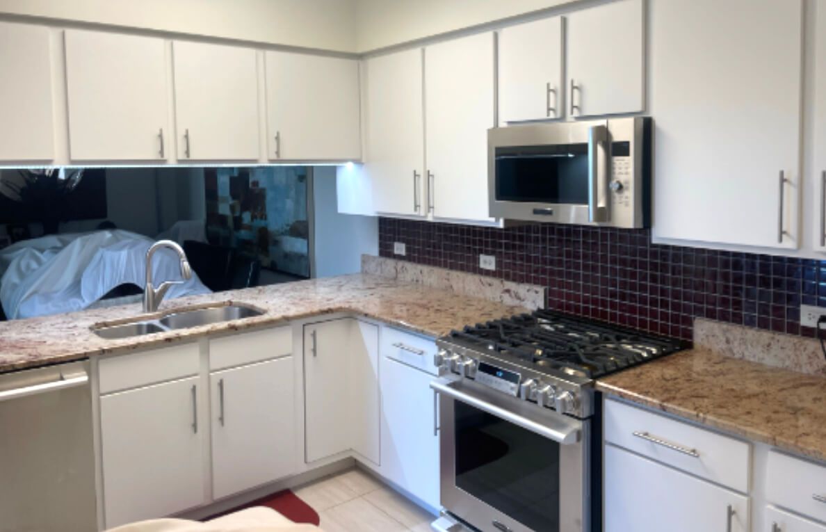 A kitchen with white cabinets and stainless steel appliances