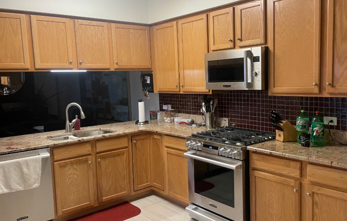 A kitchen with wooden cabinets , stainless steel appliances , granite counter tops and a stove.