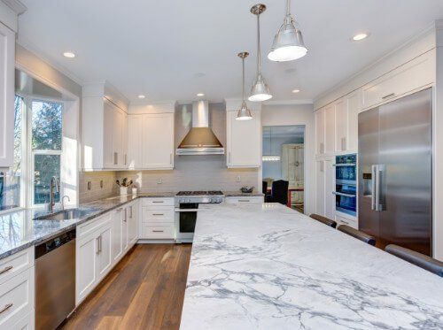 A kitchen with white cabinets , stainless steel appliances , a sink , and a stove.