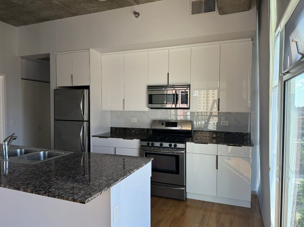 A kitchen with white cabinets , stainless steel appliances and granite counter tops.