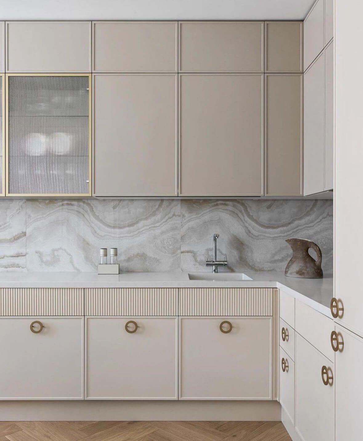 A kitchen with white cabinets , a sink , and a marble counter top.