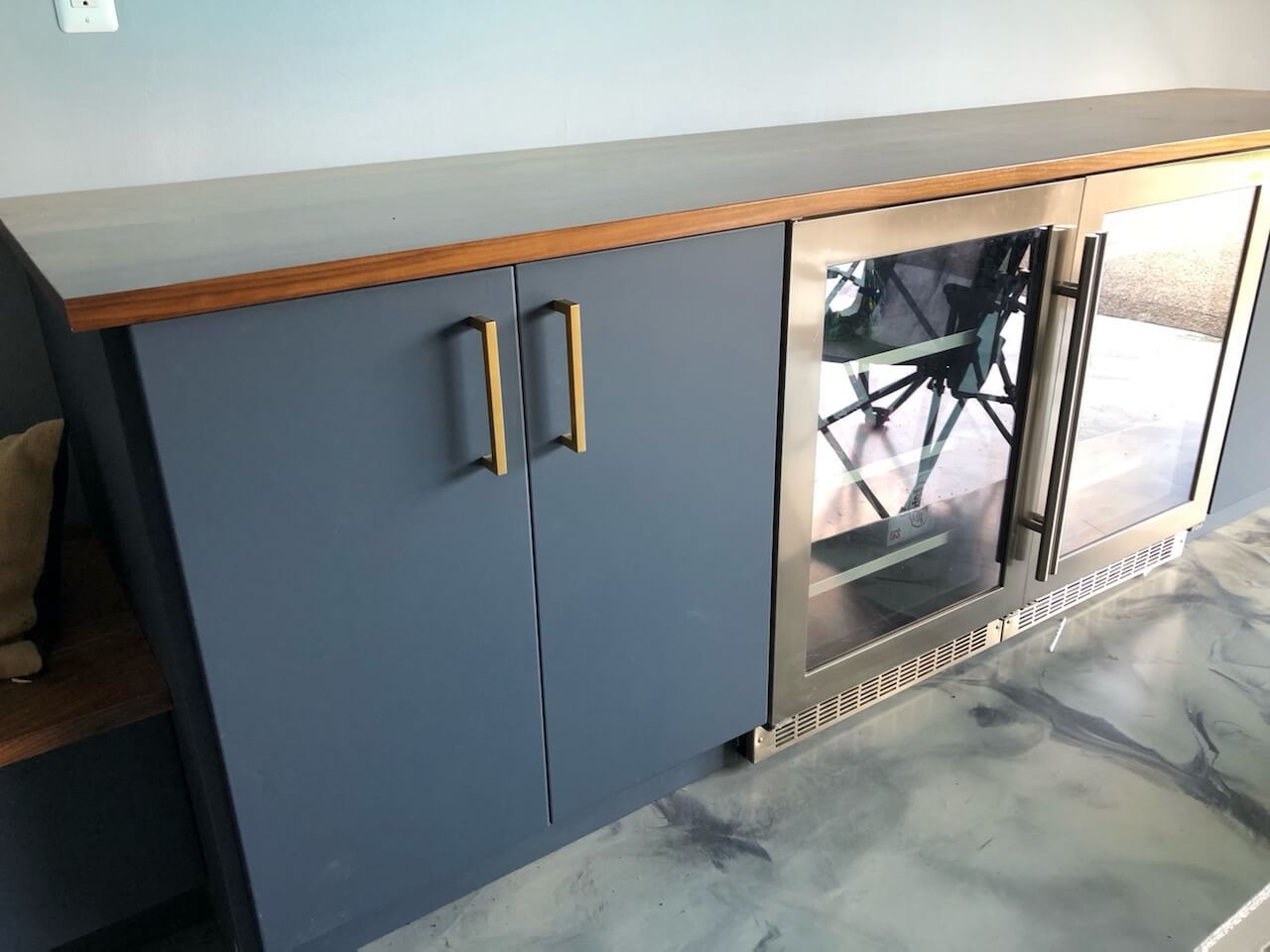 A blue cabinet with a stainless steel refrigerator inside of it.