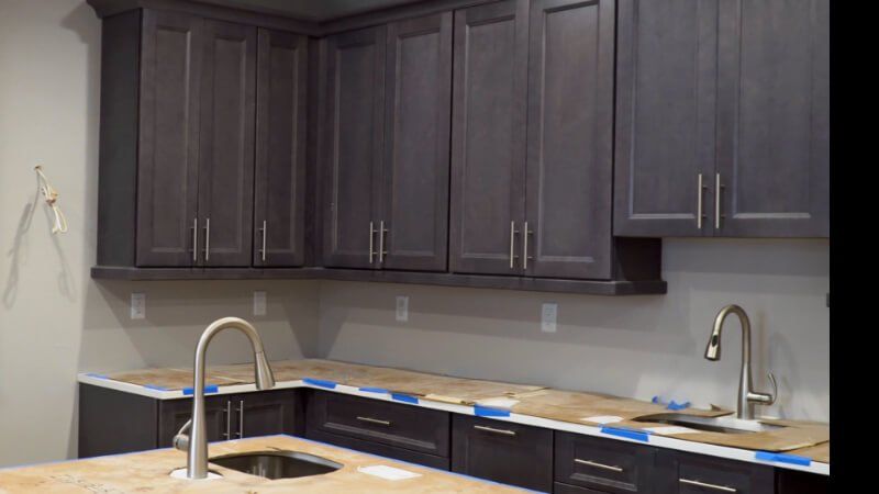 Kitchen cabinets in shades of gray, with stainless steel hardware. Granite countertops.
