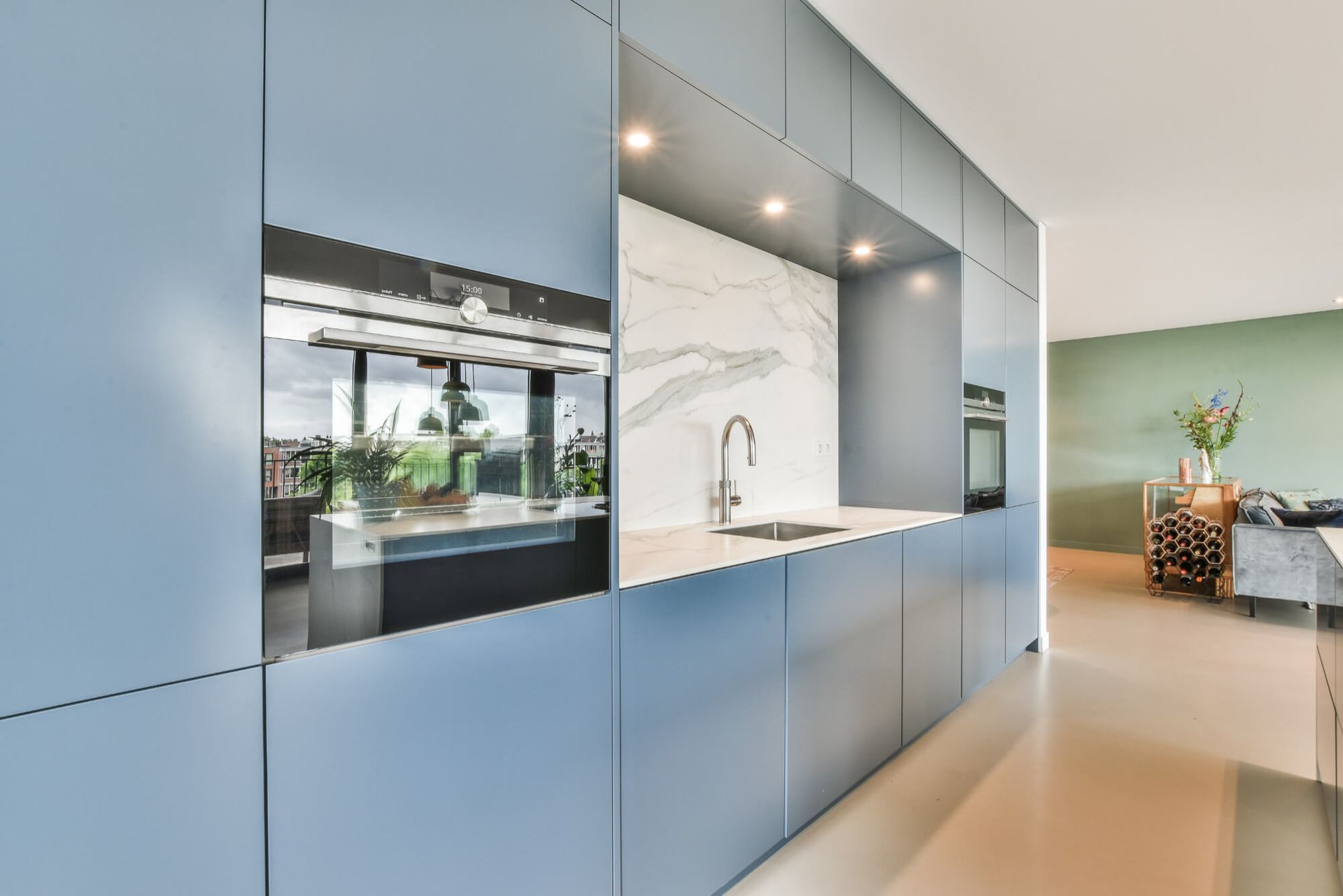 A kitchen with blue cabinets , a sink , and an oven.