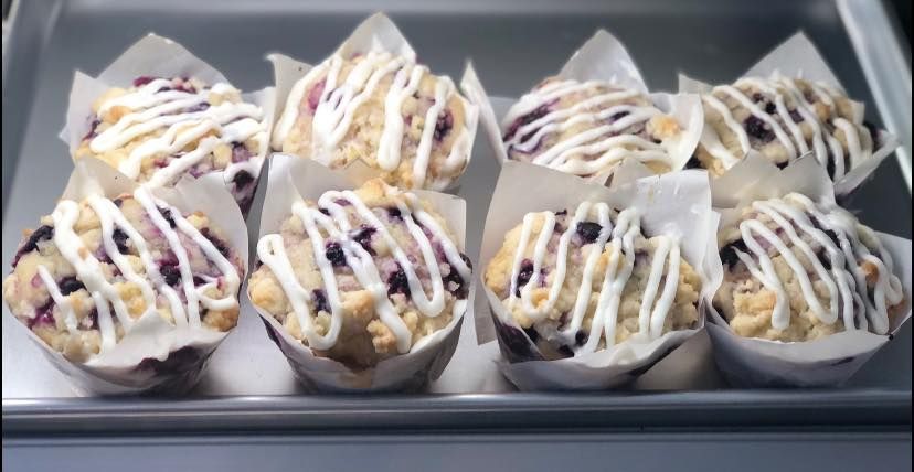 A tray of blueberry muffins with icing on them