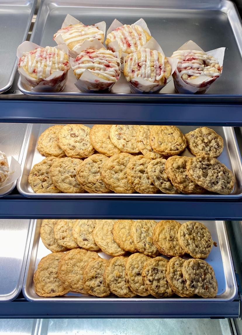 A display case filled with cookies and cupcakes in a bakery.