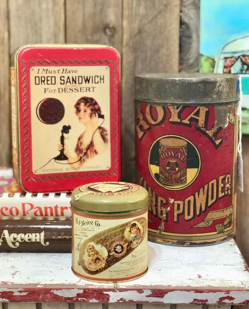 Three tins of food are sitting on a wooden table.