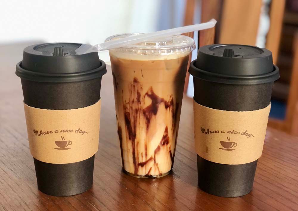 Three cups of coffee are sitting on a wooden table.