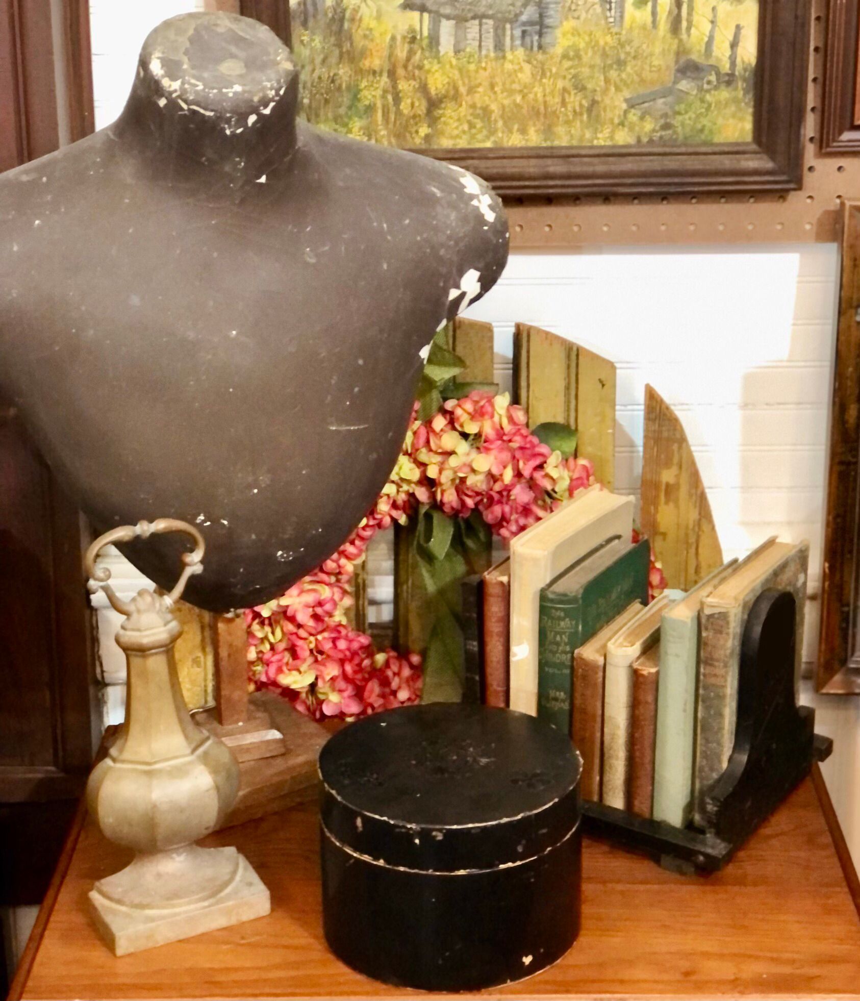A table with a statue of a woman surrounded by books and flowers