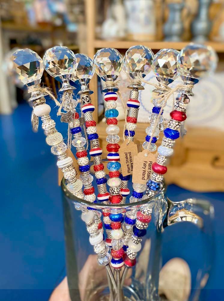 A person is holding a glass filled with red , white and blue beads.