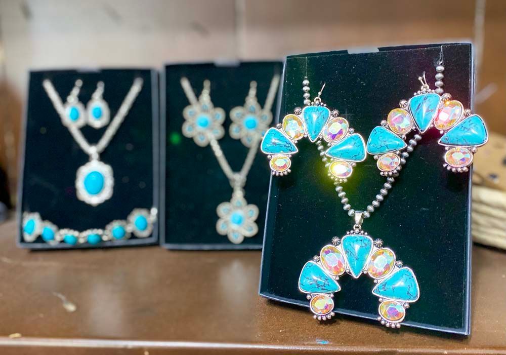 Three necklaces and earrings are on display on a table