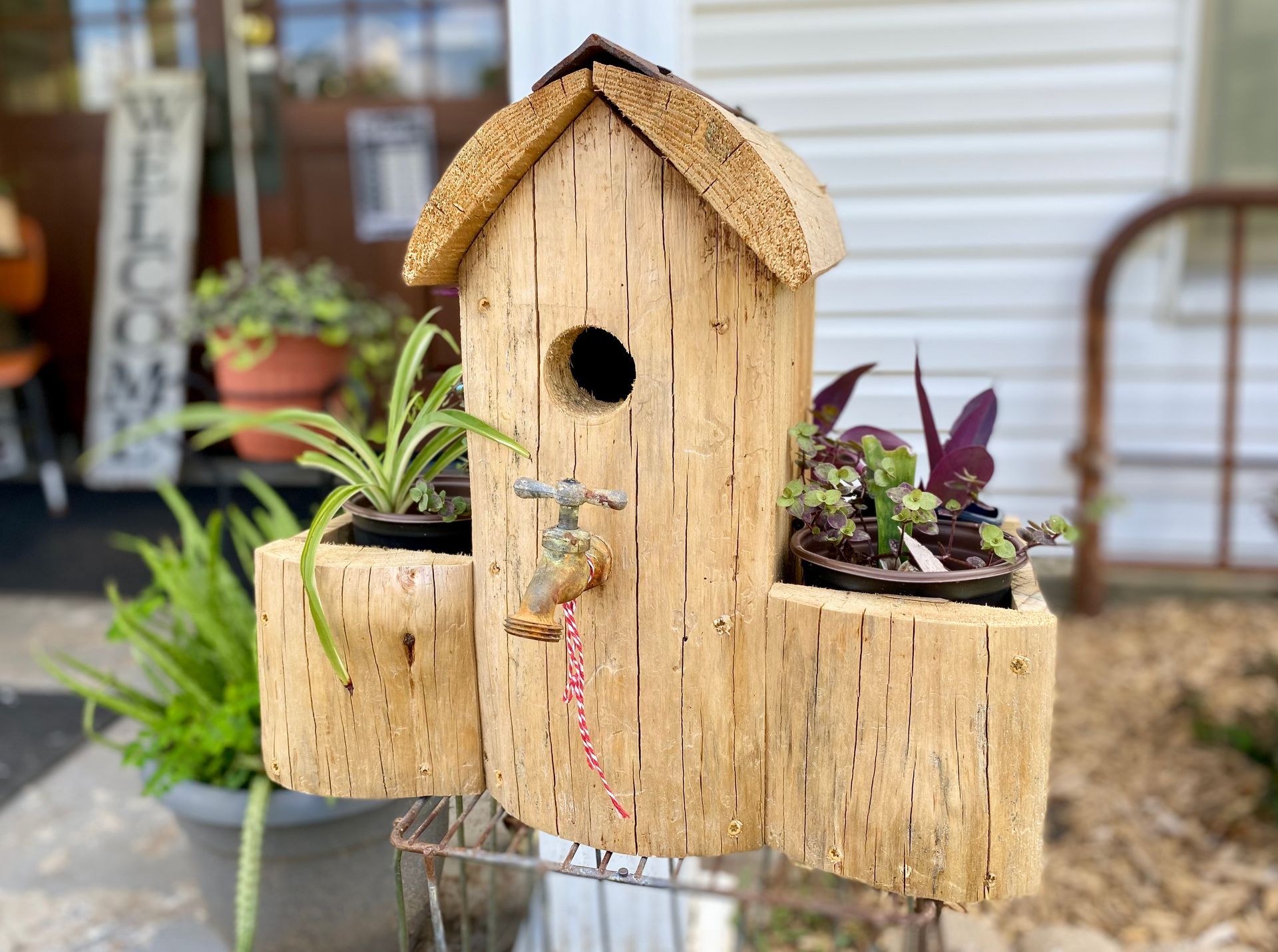 A wooden birdhouse with potted plants inside of it.