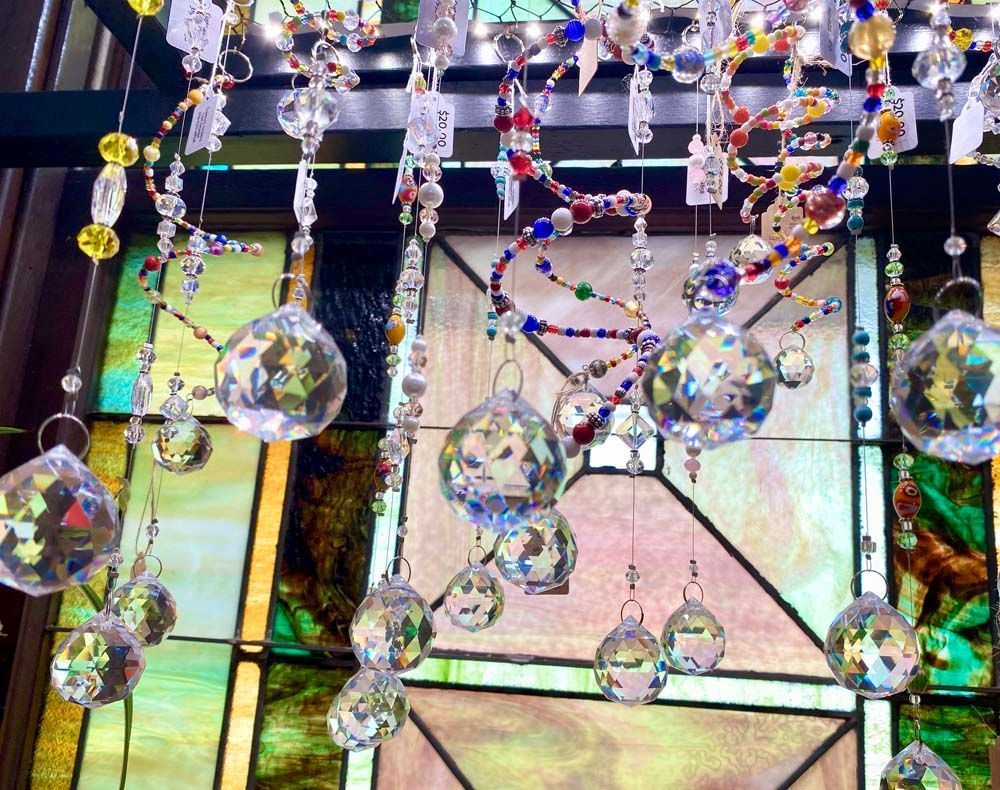 A bunch of crystals hanging from the ceiling in front of a stained glass window