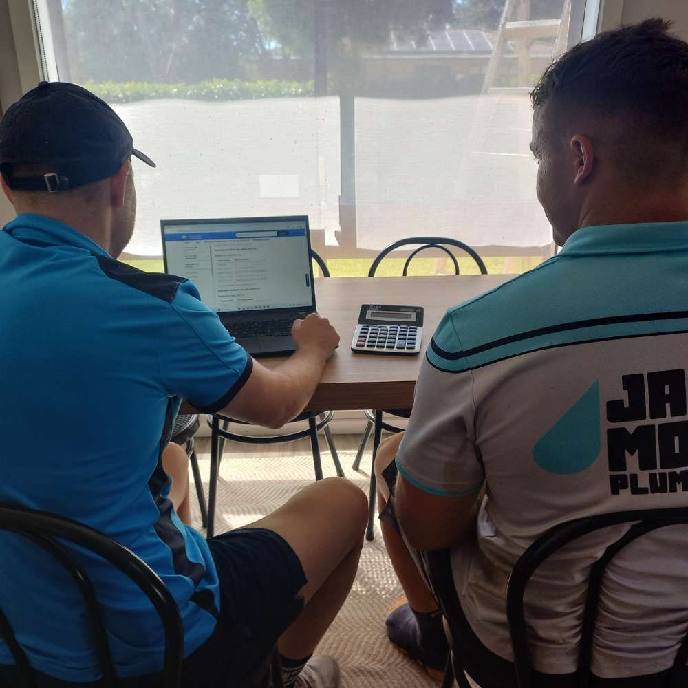 A Person Is Holding A Pen And Using A Calculator — Wagga Tradesman Accounting Services In Wagga Wagga, NSW