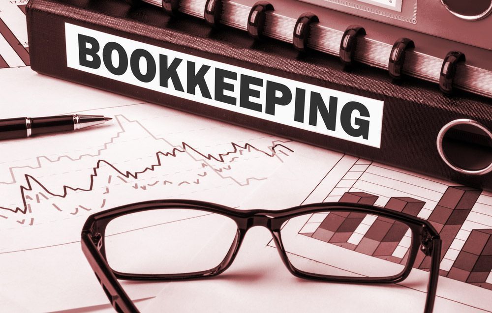A Pair Of Glasses Is Sitting On Top Of A Bookkeeping Binder — Wagga Tradesman Accounting Services In Wagga Wagga, NSW