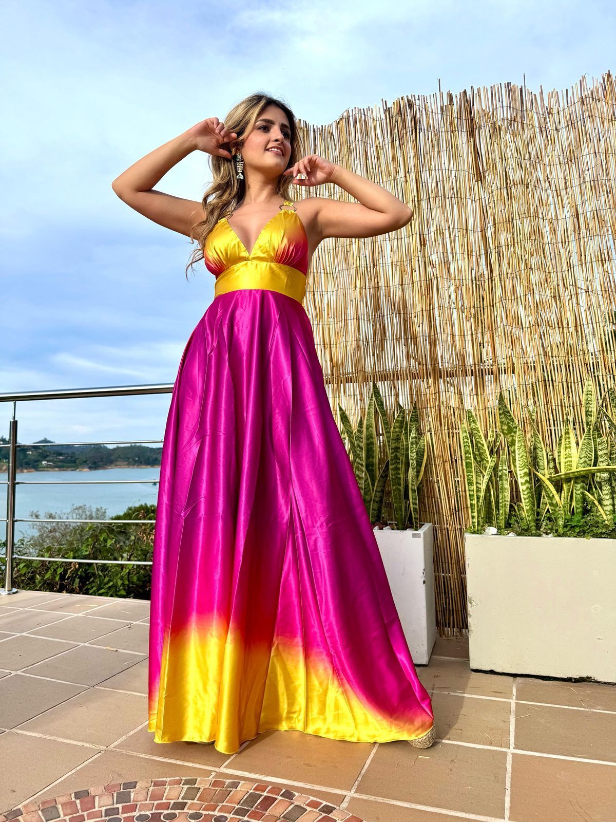 Una mujer con un vestido rosa y amarillo está parada en un balcón.