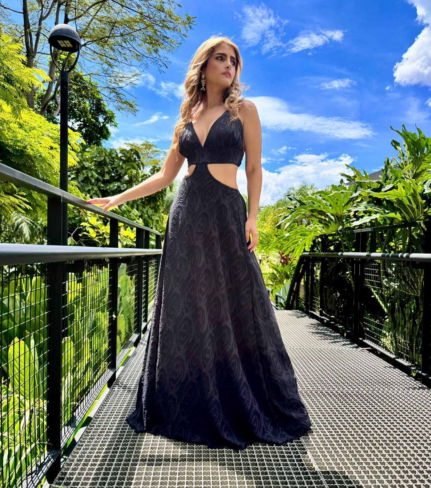 Una mujer con un vestido negro está parada en un puente.