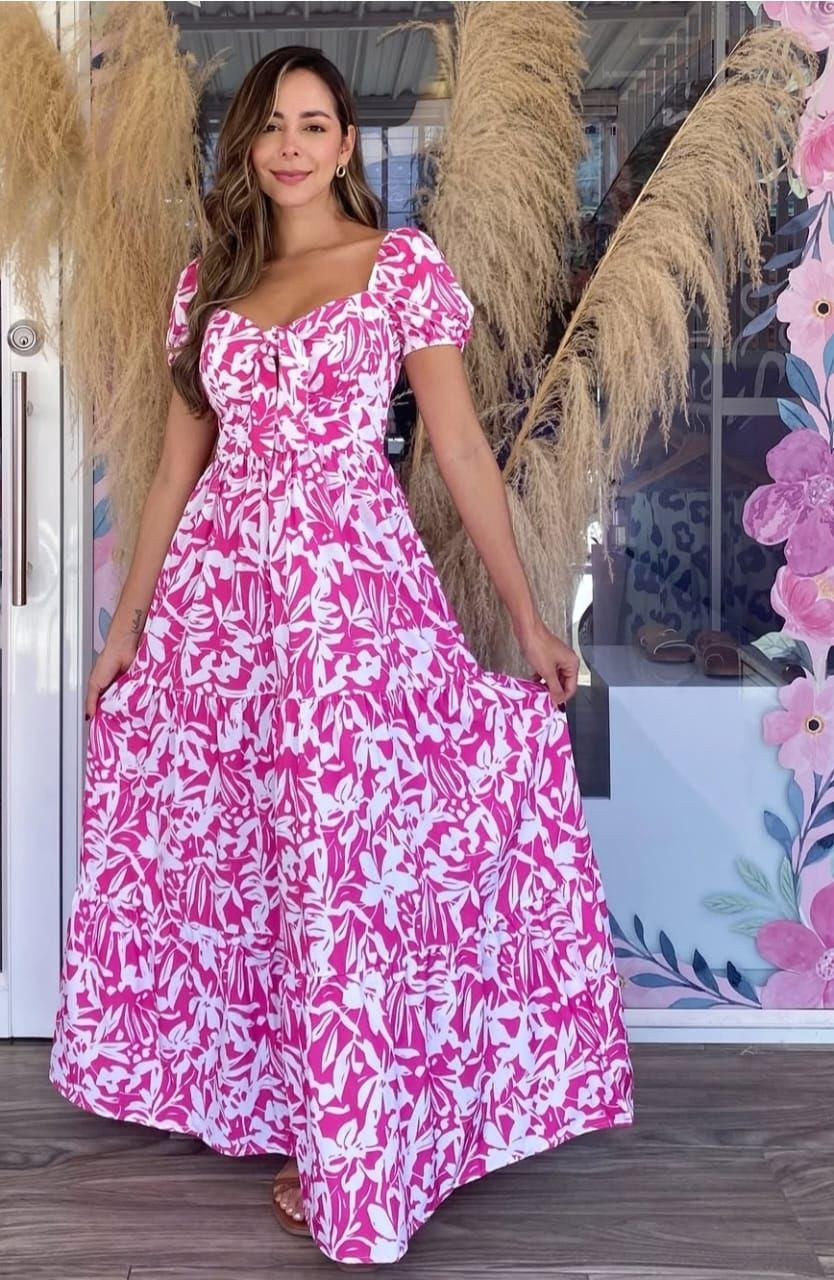 Una mujer lleva un vestido largo rosa y blanco.