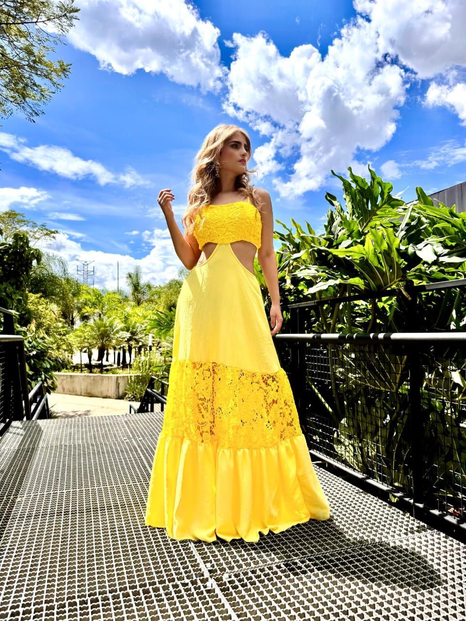 Una mujer con un vestido amarillo está parada en un puente.