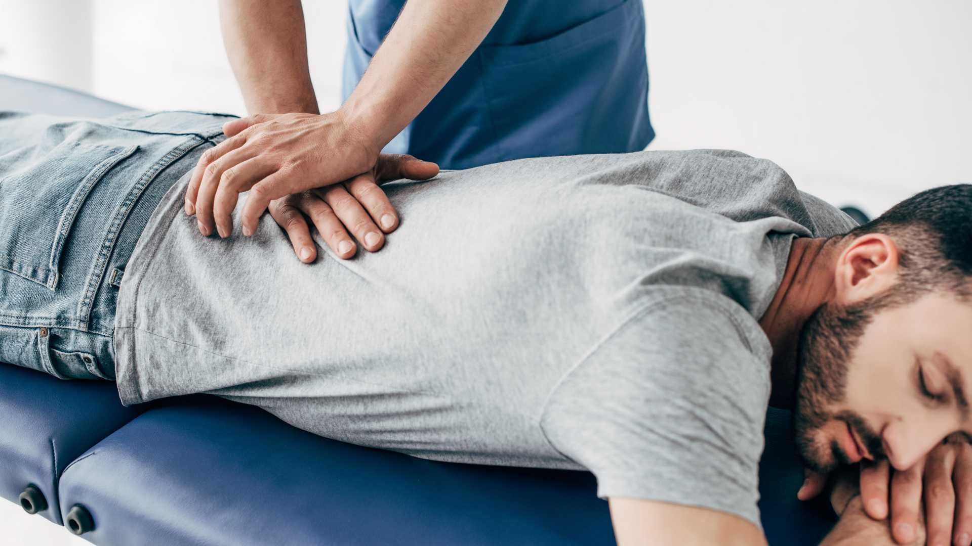 a man is laying on a table getting a massage from a nurse .