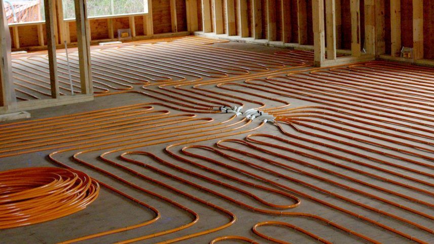 Radiant floor heating PEX tubing laid out in loops on a concrete subfloor during home construction.