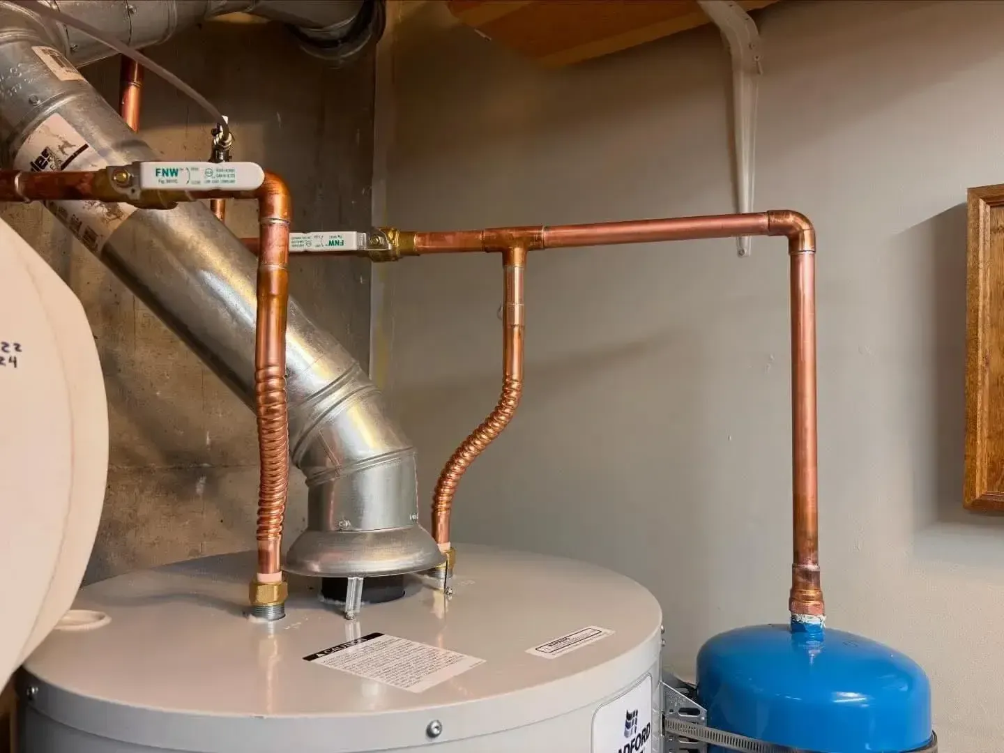A water heater with copper piping, shut-off valves, and an expansion tank attached to the top.