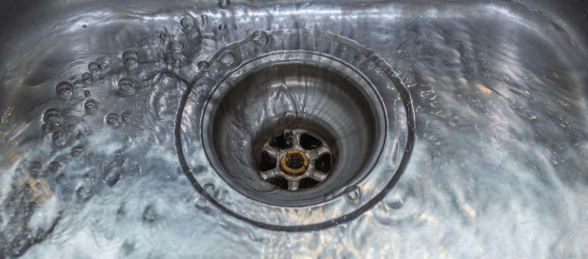 A close up of a sink with water running down the drain.