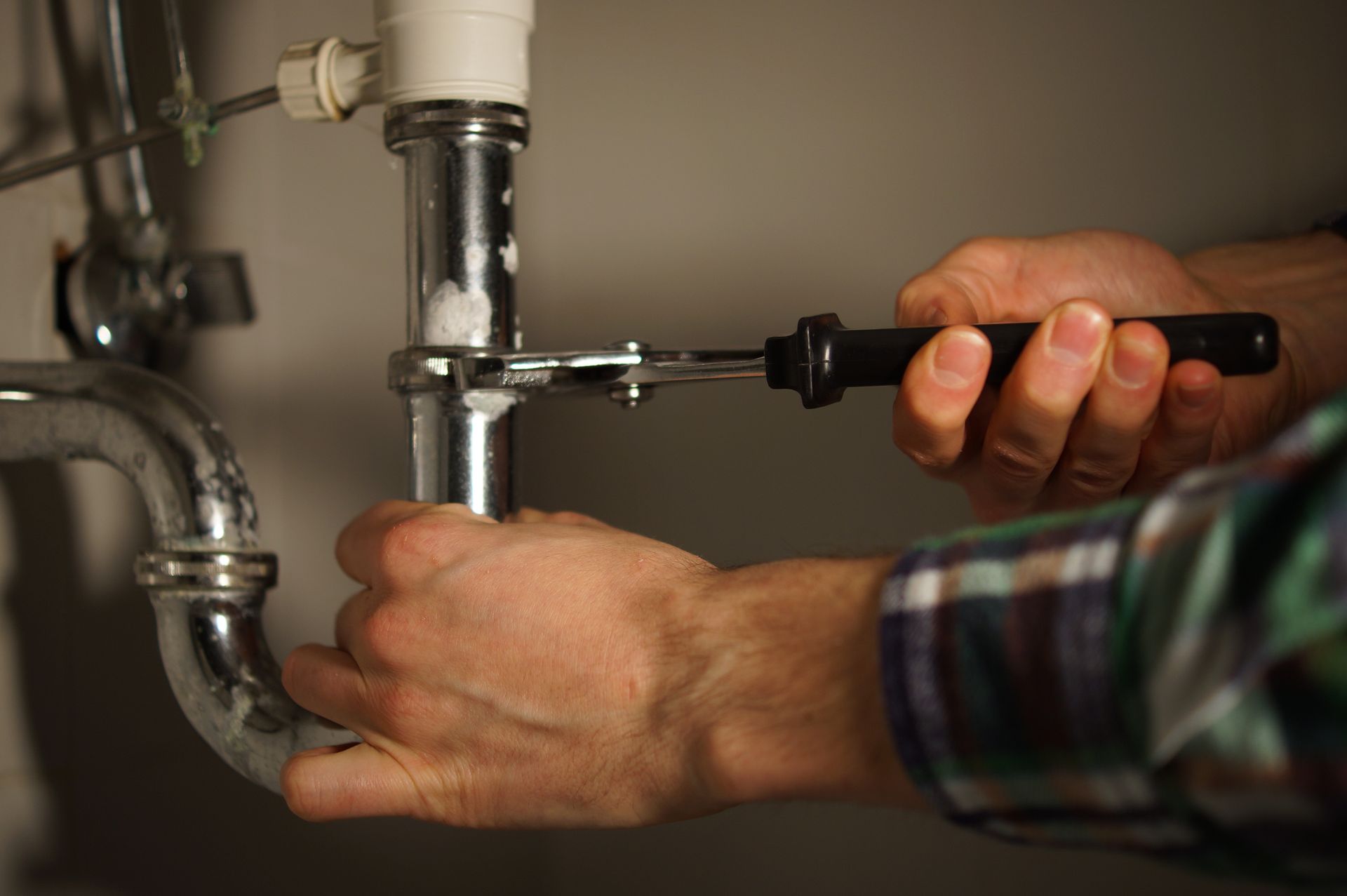 A person is fixing a faucet in a kitchen sink.