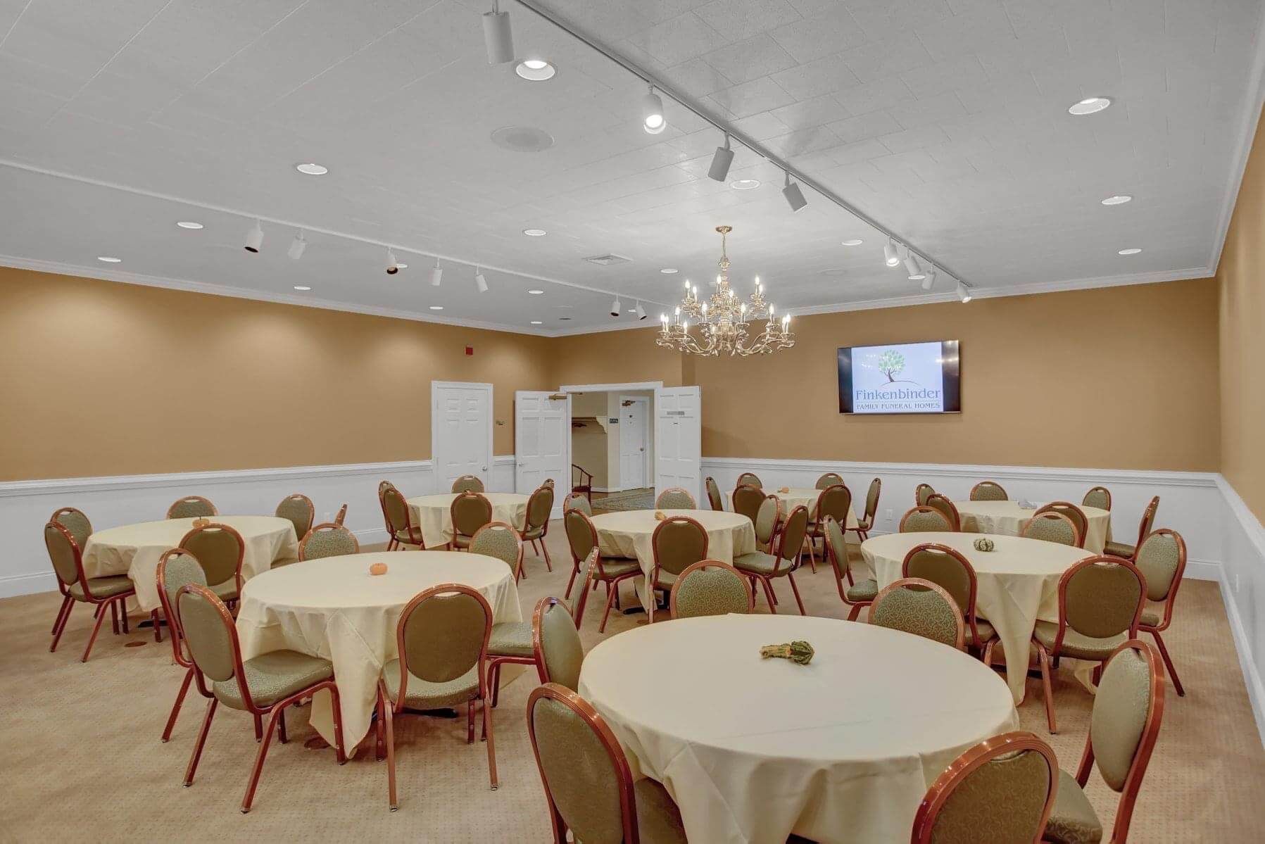 A large room with tables and chairs and a chandelier.