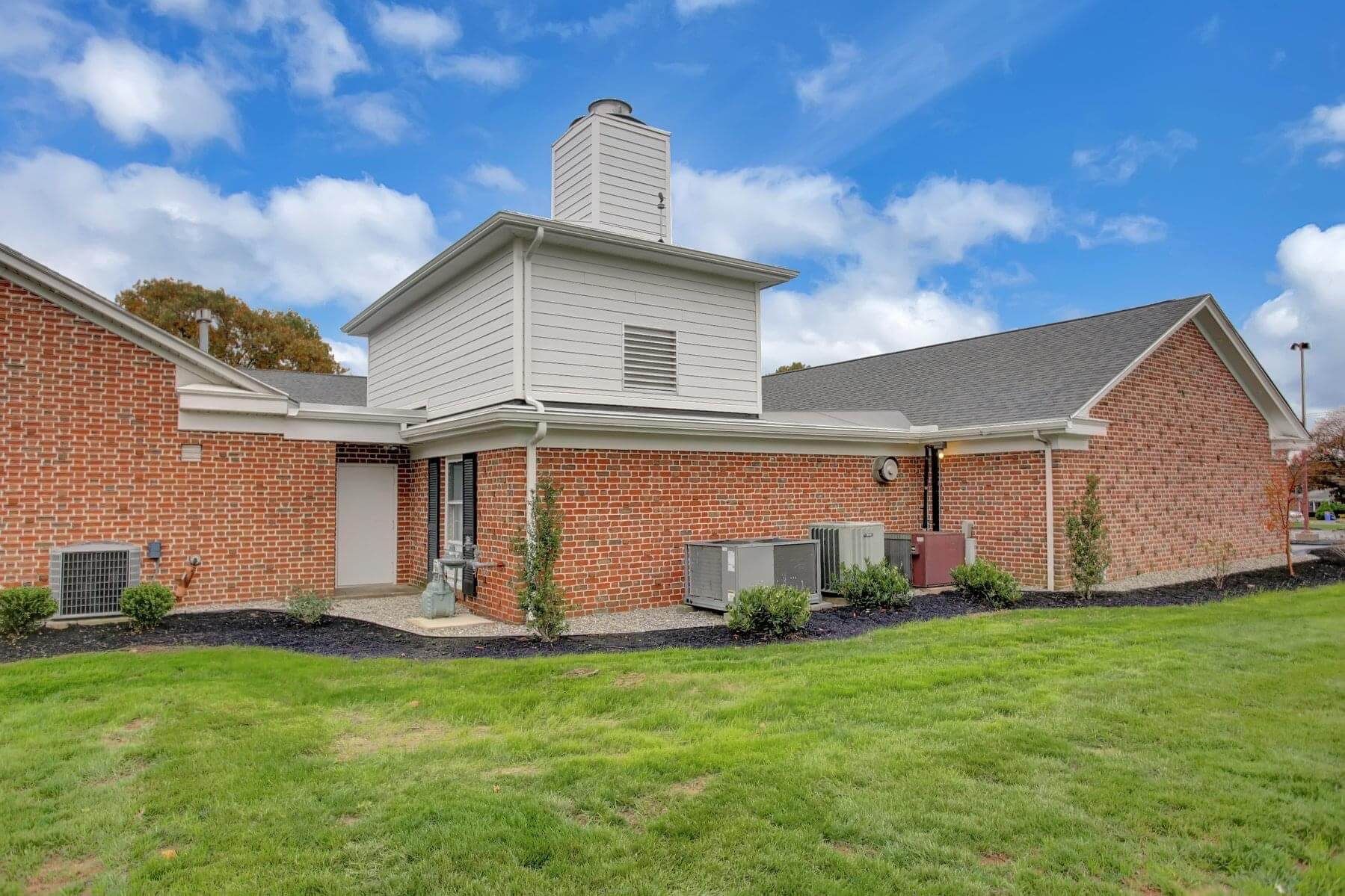 A large brick house with a large lawn in front of it.