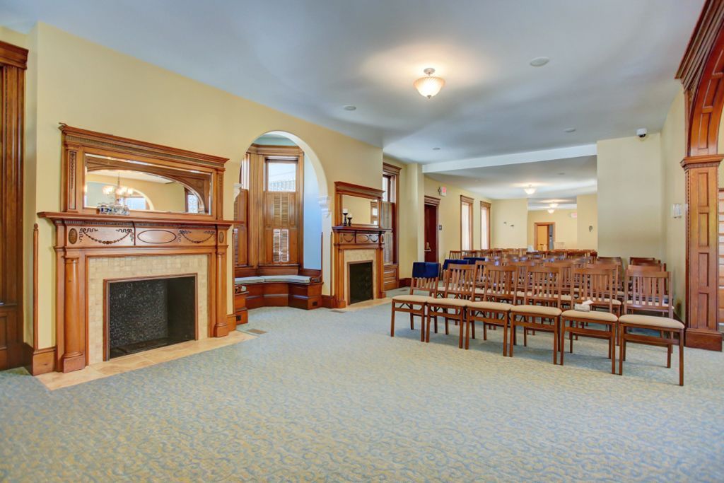 A large room with a fireplace and chairs in it