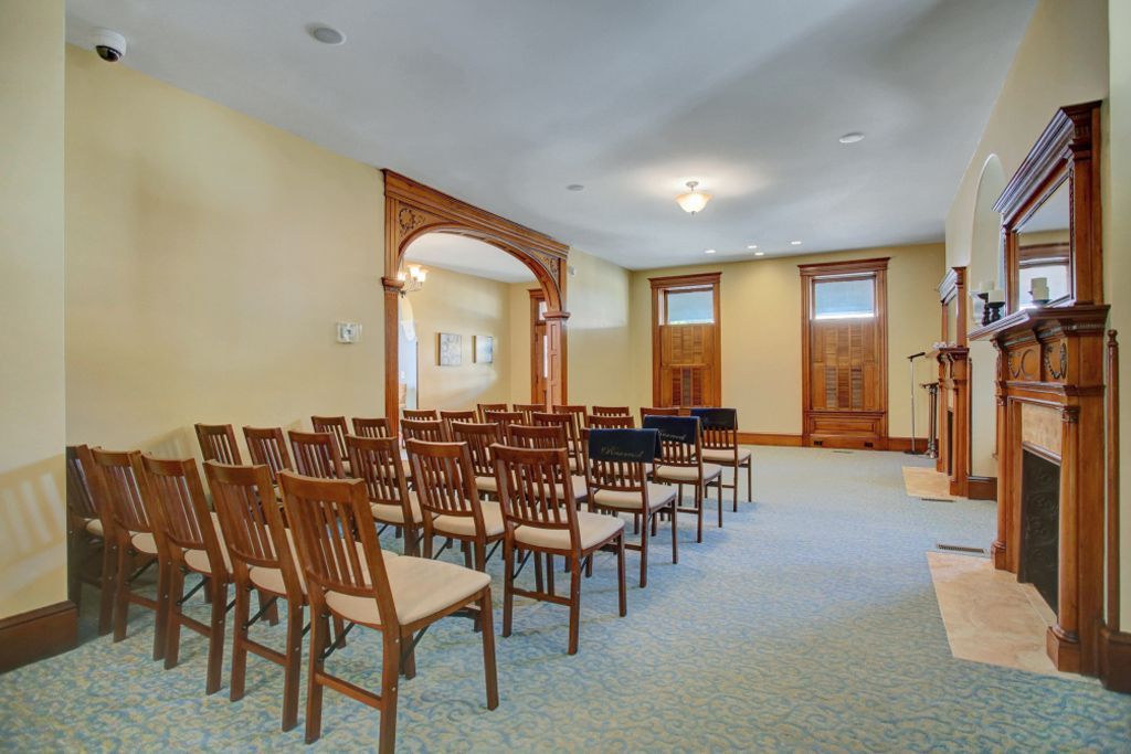 A room with rows of chairs and a fireplace