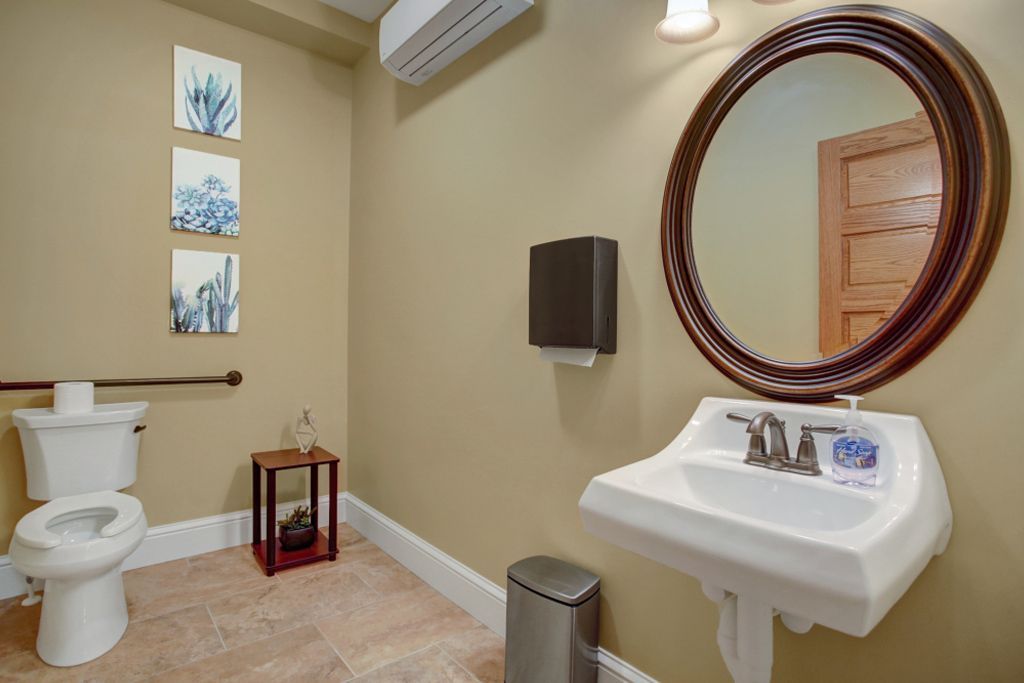 A bathroom with a toilet , sink and mirror.