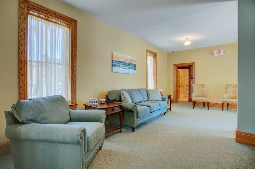 A living room with a couch , chair , table and two windows.