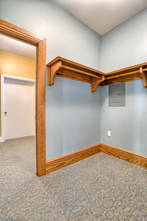 An empty walk in closet with wooden shelves and a door.