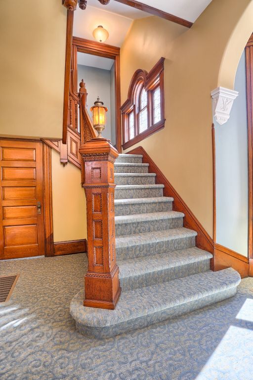 A staircase with a wooden railing and carpeted steps