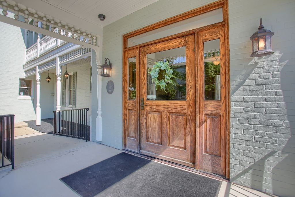 A large wooden door with a black mat in front of it