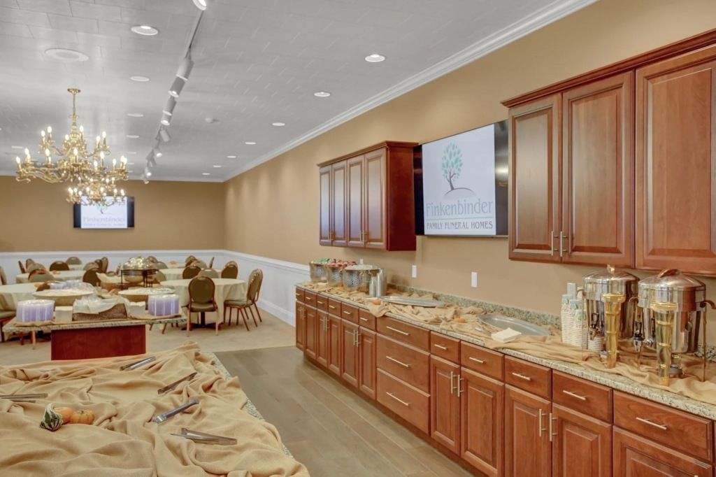 A large room with tables and chairs and a long buffet line.