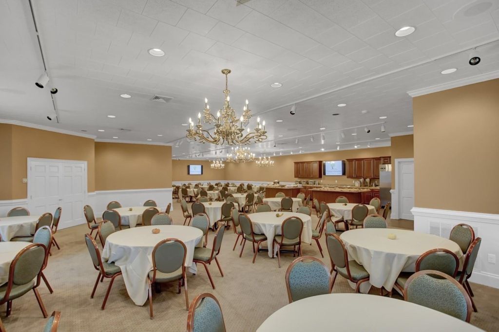 A large room with tables and chairs and a chandelier.